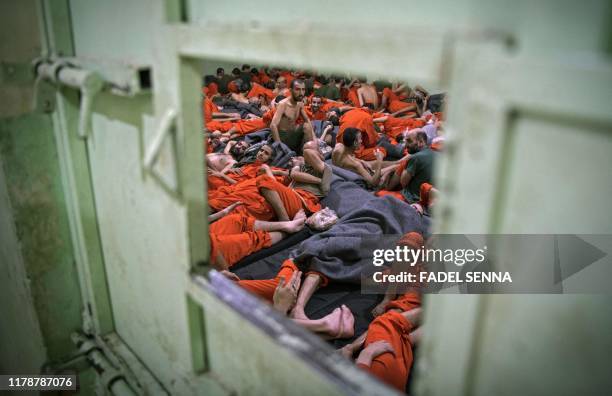 Men, suspected of being affiliated with the Islamic State group, gather in a prison cell in the northeastern Syrian city of Hasakeh on October 26,...