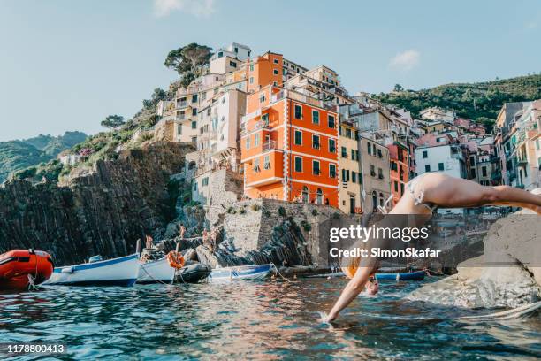 woman dipping in water, cinque terre, italy - cliff side stock pictures, royalty-free photos & images