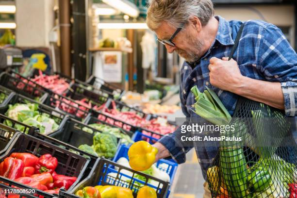 Senior Man with Fruits and Vegetables in a Black cotton mesh reusable bag, Zero Waste Shopping on Outdoors Market