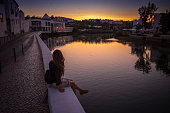 Woman enjoys a sunset view of Tavira, Portugal along the River Gilao