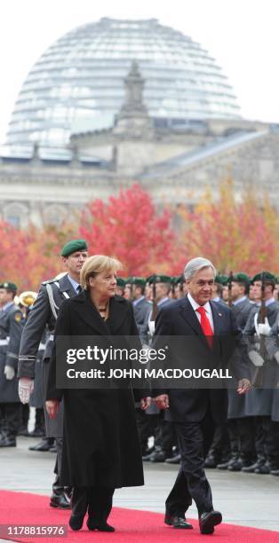 German Chancellor Angela Merkel and Chilean President Sebastian Pinera review an honour guard during a welcoming ceremony at the chancellery in...