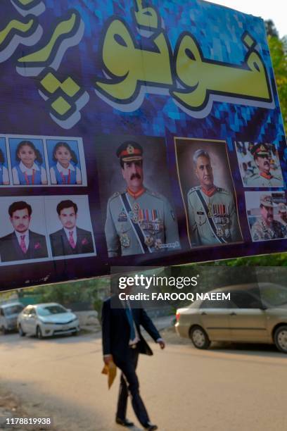 Man walks past an advertisement showing photos of former country army chief Raheel Sharif and current Army Chief General Qamar Javed Bajwa outside a...