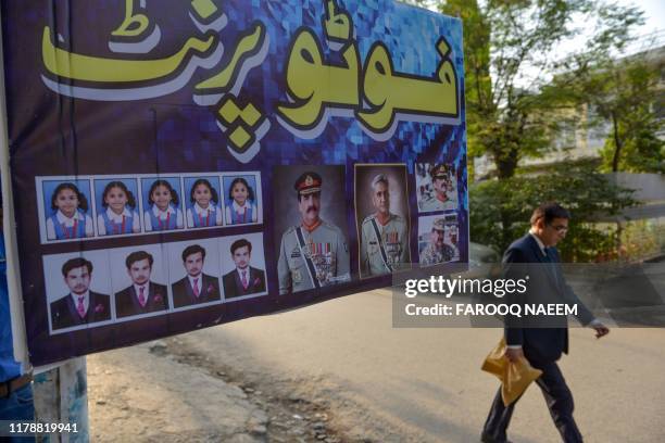 Man walks past an advertisement showing photos of former country army chief Raheel Sharif and current Army Chief General Qamar Javed Bajwa outside a...