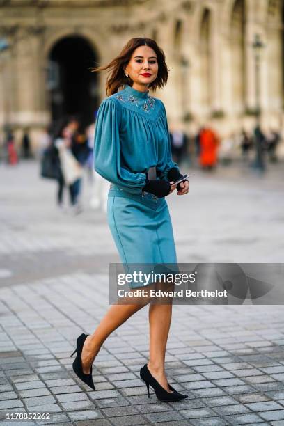 Christine Centenera wears a blue pleated dress with metallic embroidery, black shoes, a belt, outside Louis Vuitton, during Paris Fashion Week -...