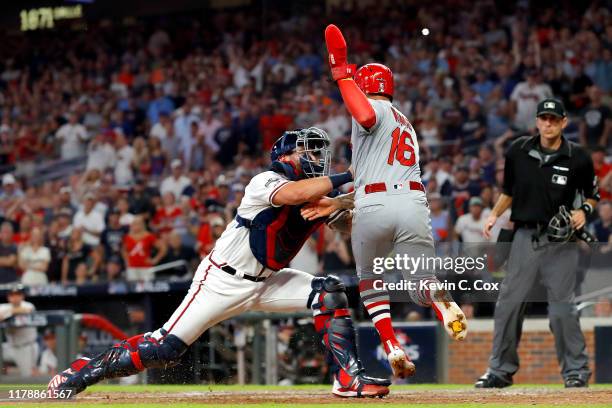 Kolten Wong of the St. Louis Cardinals is tagged out at home plate by Francisco Cervelli of the Atlanta Braves in an attempt to score from first base...