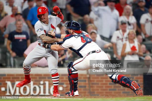 Kolten Wong of the St. Louis Cardinals is tagged out at home plate by Francisco Cervelli of the Atlanta Braves in an attempt to score from first base...