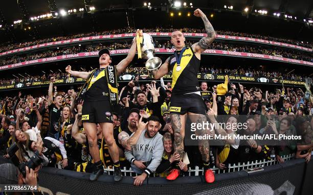 Dustin Martin and Liam Baker of the Tigers celebrate victory with the Premiership Trophy and fans during the 2019 AFL Grand Final match between the...