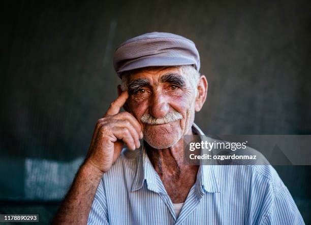 close-up portret van een senior man over donkere achtergrond - turkse etniciteit stockfoto's en -beelden