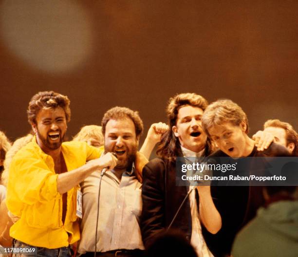 George Michael, concert promoter Harvey Goldsmith, Bono and Paul McCartney performing the Band Aid single "Do They Know It's Christmas" during the...