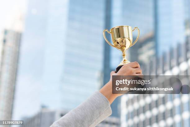 business goals,business concept.close up hand of businesswoman holding gold trophy. - concurso imagens e fotografias de stock