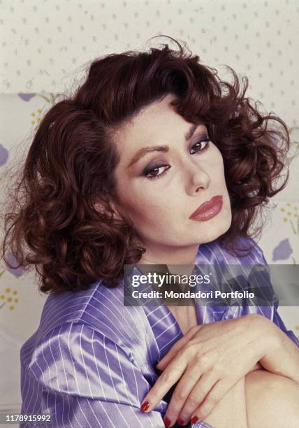 French-born Italian actress Edwige Fenech sitting on a bed. 1990