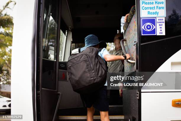 australian schoolboy boards the bus - school bus stock photos et images de collection