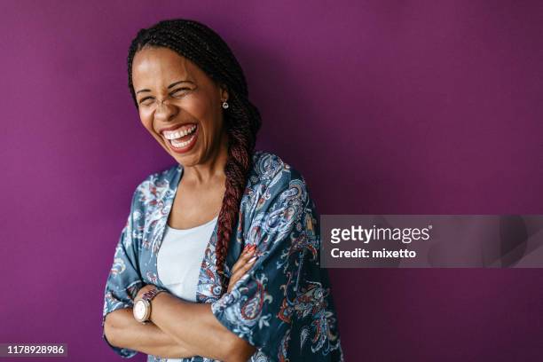 mixed race woman laughing with crossed arms - purple background stock pictures, royalty-free photos & images
