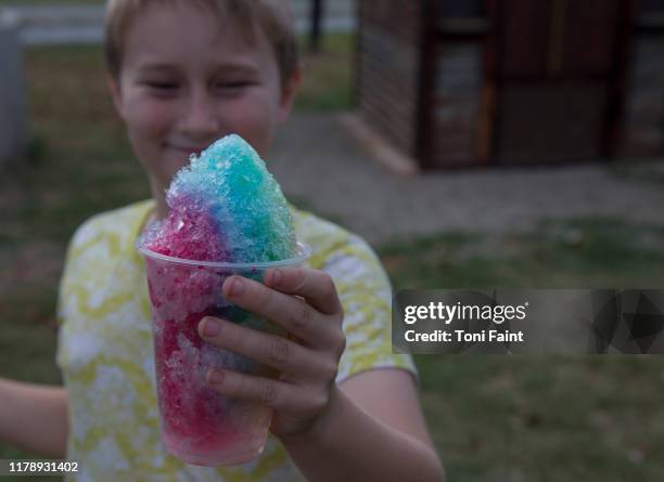 an 8 year old boy enjoying a snow cone from the markets - wassereis stock-fotos und bilder