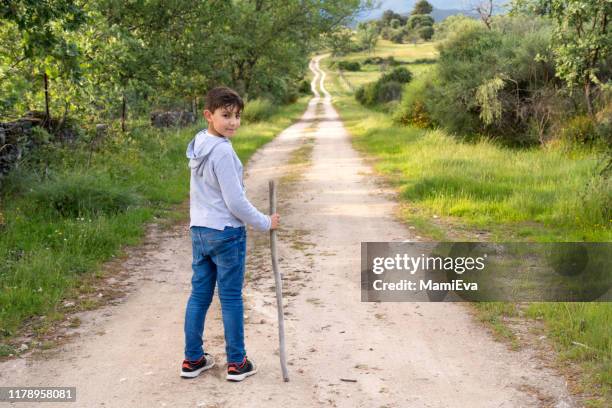 boy standing on a footpath holding a stick, spain - boy looking over shoulder stock pictures, royalty-free photos & images