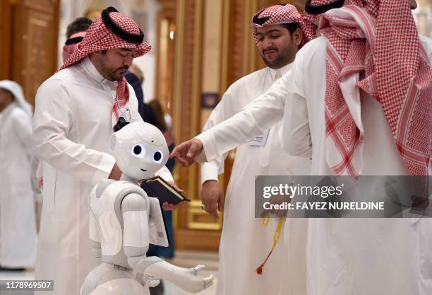 Delegates chat near a robot during the Future Investment Initiative forum at the King Abdulaziz Conference Centre in Saudi Arabia's capital Riyadh,...