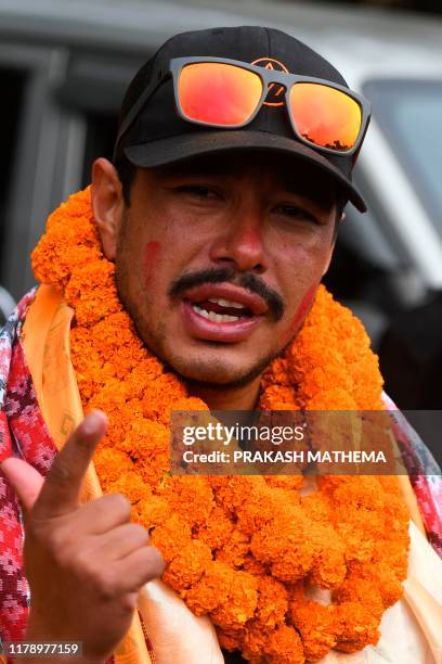 Nepali mountaineer Nirmal Purja gestures after arriving in Tribhuvan airport in Nepal's capital Kathmandu on October 30, 2019. - A Nepali mountaineer...