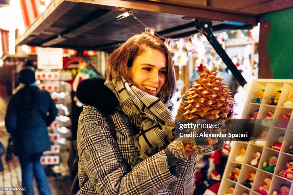 Young woman buying big pine cone at the Christmas market in Copenhagen, Denmark