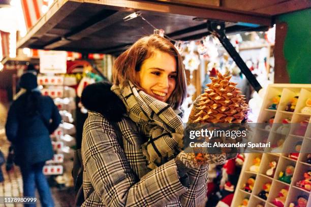 young woman buying big pine cone at the christmas market in copenhagen, denmark - copenhagen christmas market stock pictures, royalty-free photos & images