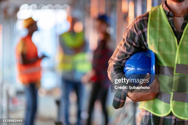 mann hält blauhelm aus nächster nähe - construction industry stock-fotos und bilder