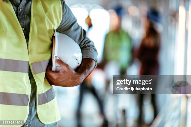 architect worker holding white helmet a for workers security control at city site - hardhat stock pictures, royalty-free photos & images