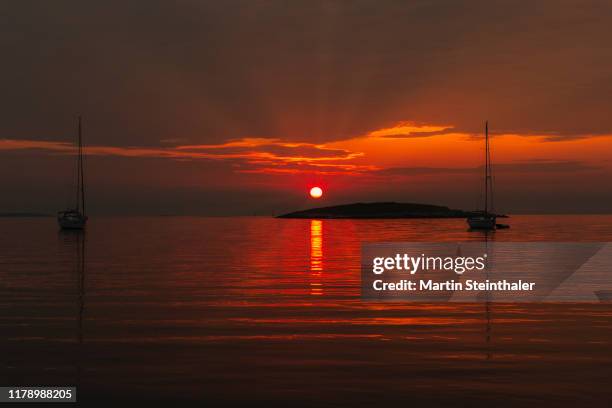 oranger sonnenuntergang am meer mit insel - stimmungsvoller himmel - stimmungsvoller himmel fotografías e imágenes de stock