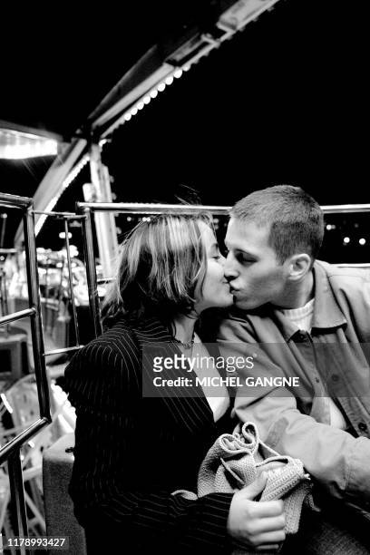 Un jeune couple s'embrasse dans un manège d'une fête foraine, en mars 2005 dans le centre ville de Bordeaux. AFP PHOTO MICHEL GANGNE