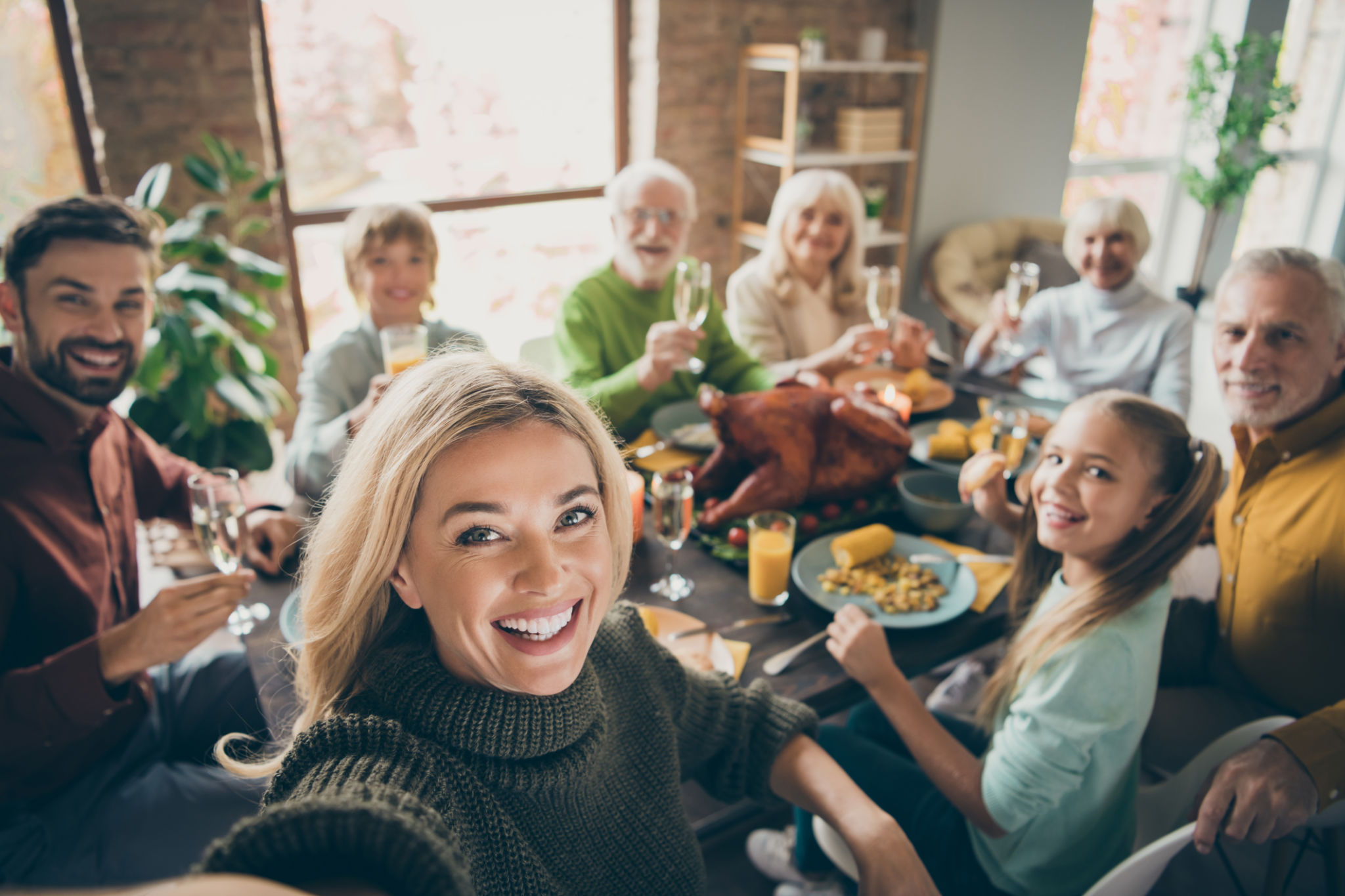 Photo of big family sit feast dishes table around roasted turkey multi-generation relatives making group selfies raising wine glasses juice in living room indoors Photo of big family sit feast dishes table around roasted turkey multi-generation relatives making group selfies raising wine glasses juice in living room indoors
