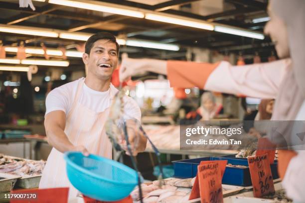 an asian malay female pick up a tiger prawn and putting it into the basket given by fish stall vendor in wet market - malayan tiger stock pictures, royalty-free photos & images