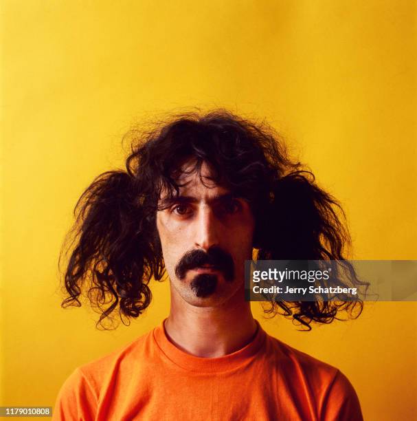 Portrait of American Rock, Jazz, and Experimental musician, composer, and bandleader Frank Zappa , with his hair in pigtails and dressed in an orange...