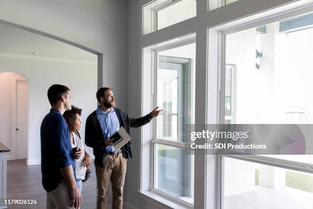 männlicher makler zeigt ein paar ein schönes haus - wohnungsbesichtigung stock-fotos und bilder