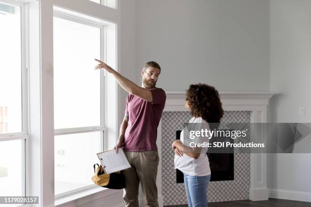 home inspector points to something outside while talking with homeowner - quality control inspector stock pictures, royalty-free photos & images