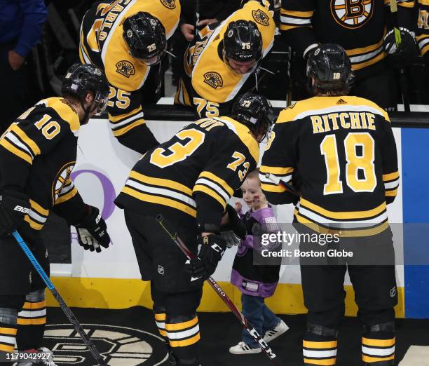 Three-year-old Quinn Waters, aka "The Mighty Quinn" of Weymouth, is congratulated by Bruins players after dropping a ceremonial puck before the game....