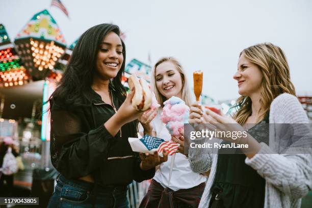 teenage women friend group enjoying state fair food - farmer's market imagens e fotografias de stock