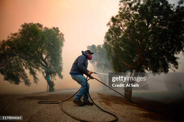 Billy Macfarlane uses garden hose to put out embers threatening his family's ranch on Tierra Rejada Road as the Easy fire approaches October 30, 2019...