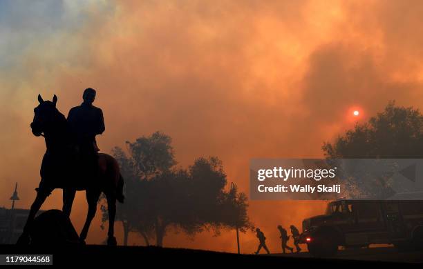 Statue of former U.S. President Ronald Reagan titled "Along The Trail" stands outside the Reagan Presidential Library as the Easy Fire burns on...