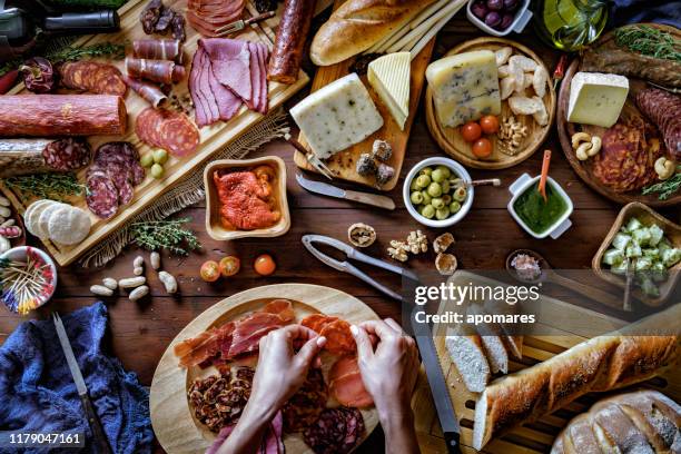 vrouwelijke handen voorbereiding van hapjes en hapjes in een set vol met diverse gezouten ham en kaas op rustiek hout - iberian stockfoto's en -beelden