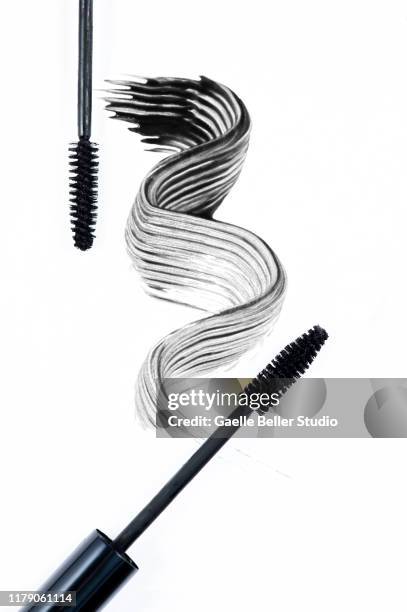 two mascara brushes next to a swirl of black mascara - mascaras 個照片及圖片檔