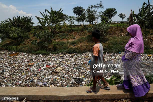 Children walk beside a river covered by garbage in Bekasi, West Java, Indonesia, on Wednesday, October 30, 2019. Plastic pollution in Indonesia is...