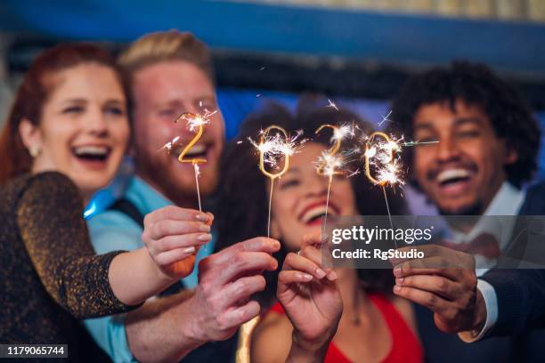 smiling people holding sparklers - 2018 new year stock pictures, royalty-free photos & images