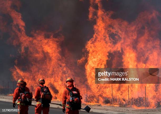 Inmate firefighters prepare to put out flames on the road leading to the Reagan Library during the Easy Fire in Simi Valley, California on October...