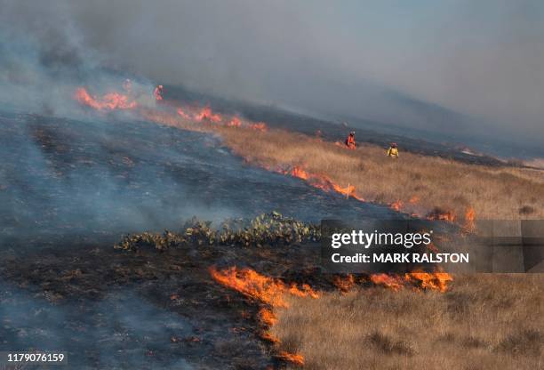 Firefighters prepare to put out flames on the road leading to the Reagan Library during the Easy Fire in Simi Valley, California on October 30, 2019....