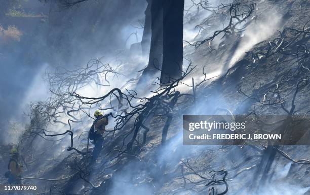 Firefighters work on a charred hillside near homes and the 118 Freeway in Simi Valley, California on October 30, 2019 after the so-called Yosemite...