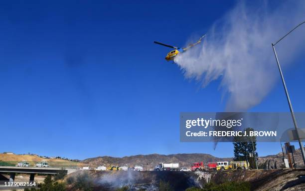 Helicopter drops water near the 118 Freeway in Simi Valley, California on October 30, 2019 after the so-called Yosemite Fire began in Simi Valley...