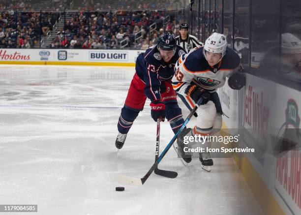 Columbus Blue Jackets right wing Cam Atkinson and Edmonton Oilers center Ryan Nugent-Hopkins battle for the puck along the boards during the game...