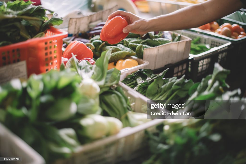 An asian malay grandfather buying from a vegetable stall in the market