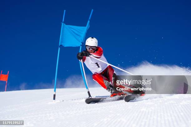 skieur professionnel de super g près du drapeau bleu de poteaux - super g skiing photos et images de collection