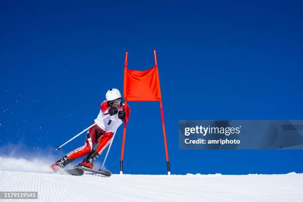 skieur en costume de course pendant l'entraînement de ski super g près du drapeau rouge de pôles aux conditions météorologiques parfaites - super g skiing photos et images de collection