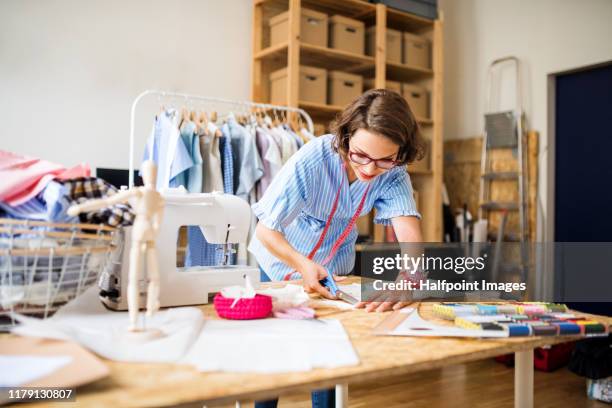 a portrait of young creative woman indoors making old clothes new and trendy. - seam stockfoto's en -beelden