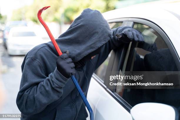 thief in a balaclava stealing woman's bag from car - car theft stock pictures, royalty-free photos & images